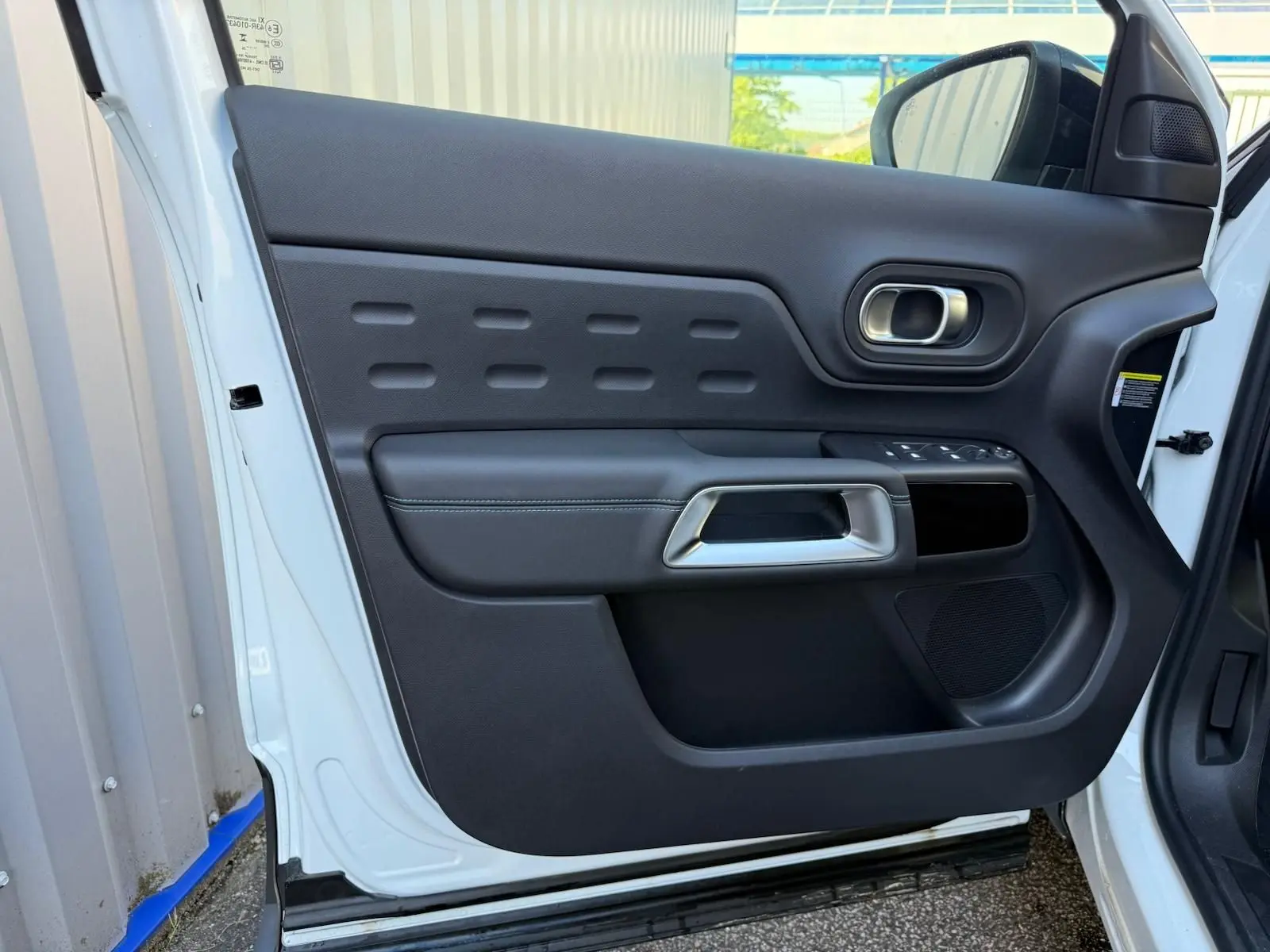 Vue rapprochée de la porte avant gauche blanche banquise du Citroën C5 Aircross 2024 avec garniture noire et poignée argentée.