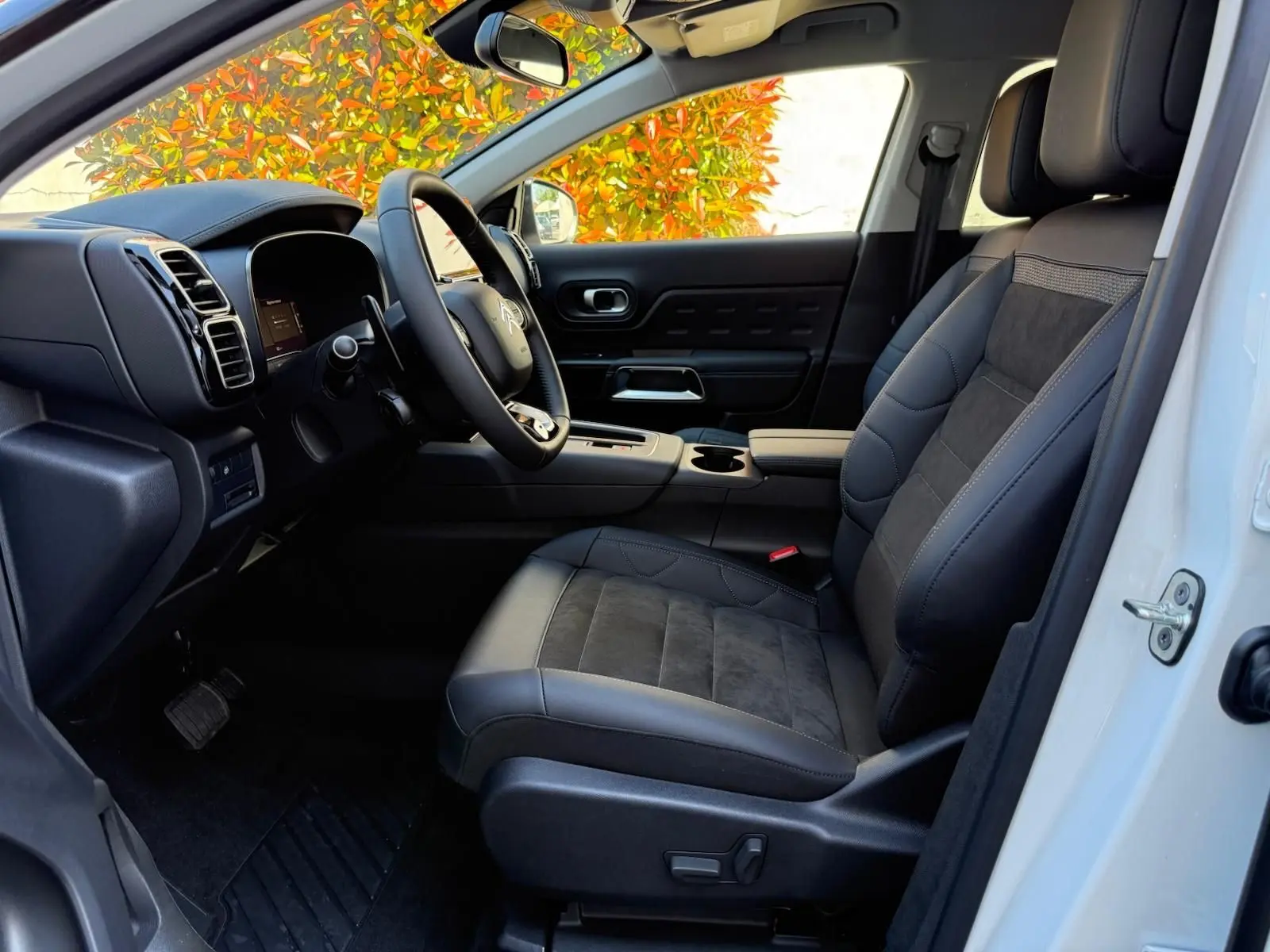 Intérieur côté conducteur du Citroën C5 Aircross blanc banquise 2024, sièges cuir et alcantara noirs avec tableau de bord moderne.