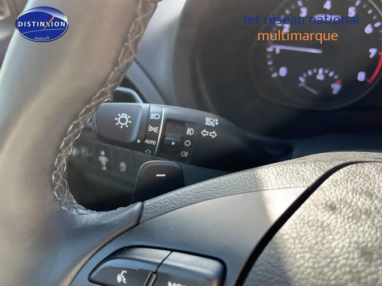 Gros plan sur le volant cuir multifonction et les commandes d'éclairage d'une Hyundai i30 gris argent 2024.