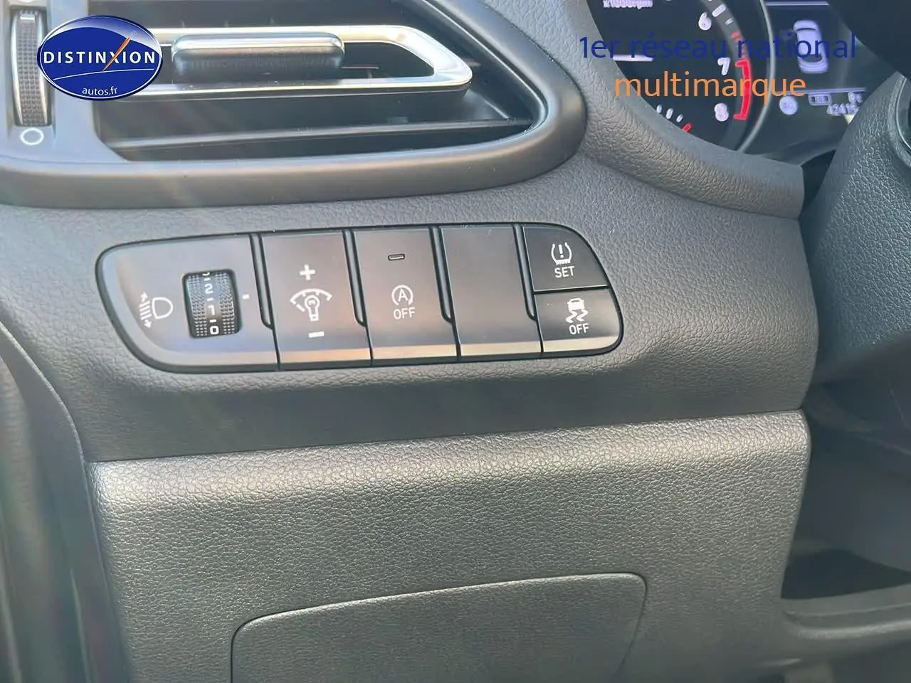 Tableau de bord côté gauche de la Hyundai i30 gris argent 2024 avec commandes d'éclairage et assistances visibles.