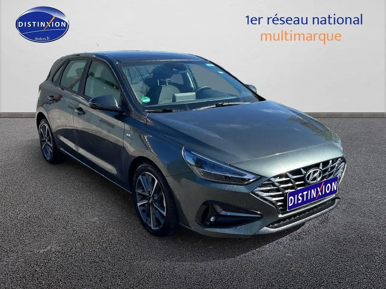 Hyundai i30 gris argent vue 3/4 avant droit avec calandre chromée et jantes alliage distinctives.