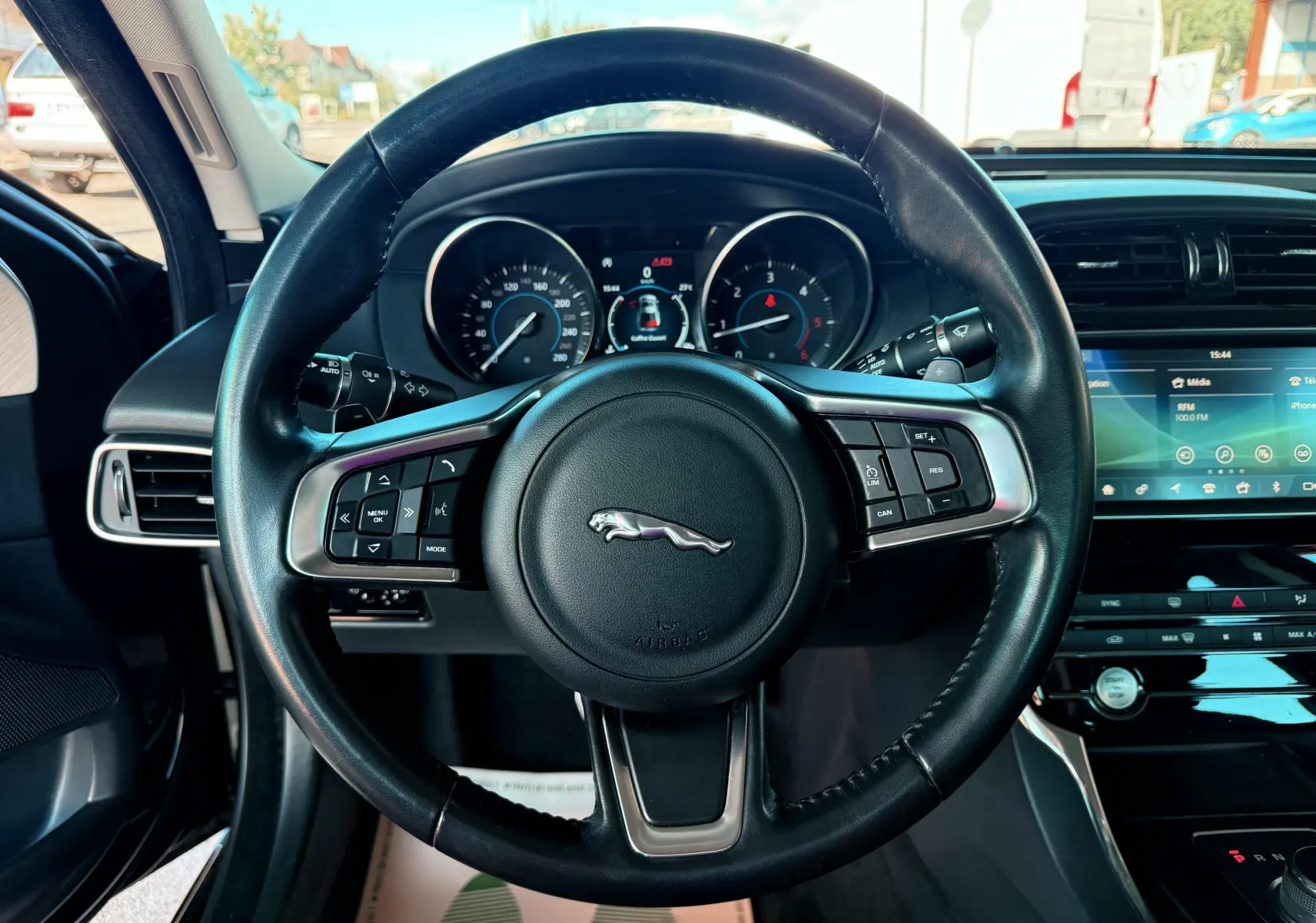 Vue centrée sur le volant en cuir noir de la Jaguar XE 2019 avec tableau de bord et écran tactile visibles.