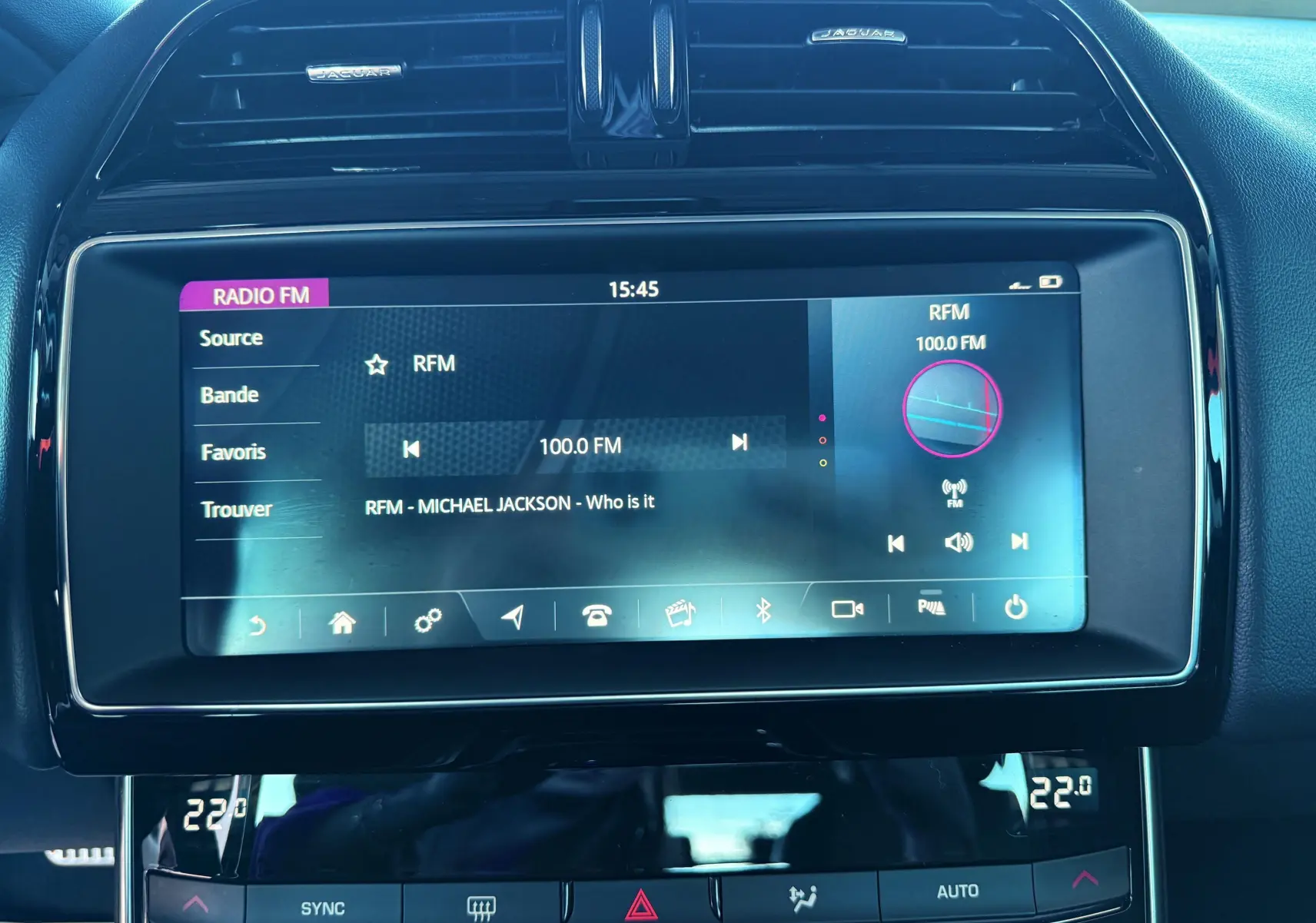 Écran tactile central de la Jaguar XE 2019 affichant la radio FM avec interface moderne et finition noire brillante.