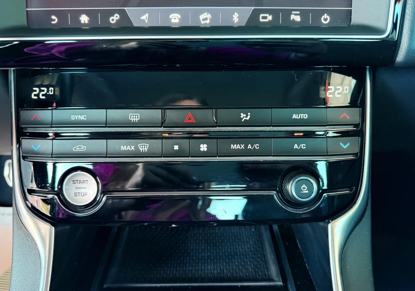 Vue rapprochée de la console centrale noire de la Jaguar XE 2019 avec commandes climatisation et bouton start/stop.