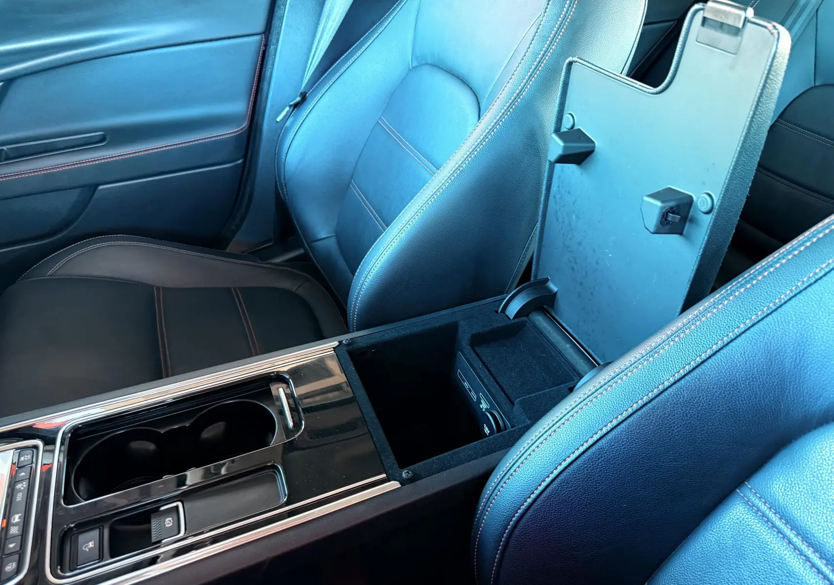 Intérieur noir cuir de la Jaguar XE 2.0D 2019, vue rapprochée sur la console centrale ouverte entre les sièges avant.