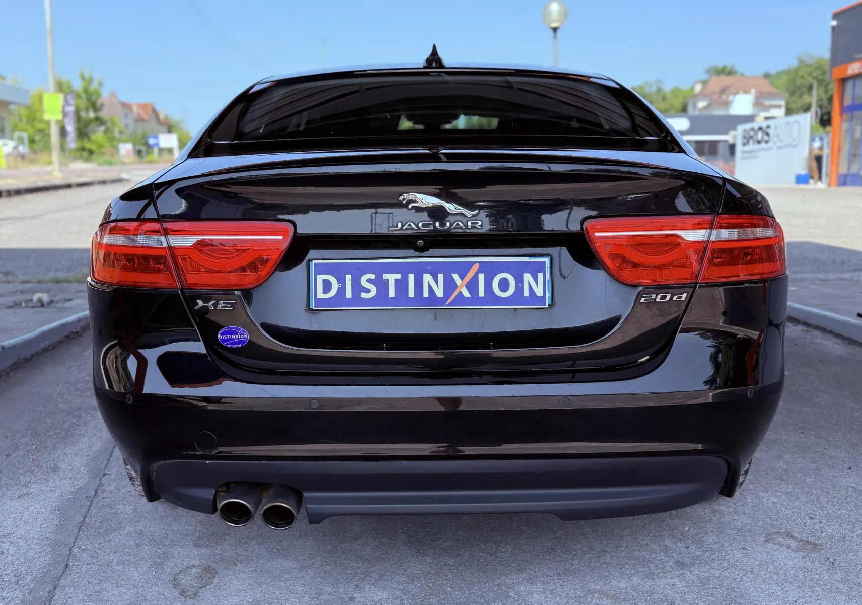 Vue arrière d'une Jaguar XE noire de 2019 avec double sortie d'échappement et logo distinctif sur le coffre.