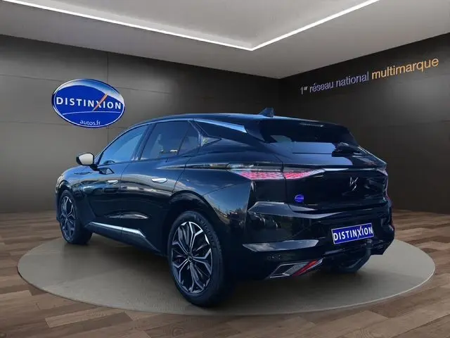 Vue 3/4 arrière droite d'une DS4 noire 2022 avec jantes bi-ton et feux arrière LED distinctifs dans un showroom.