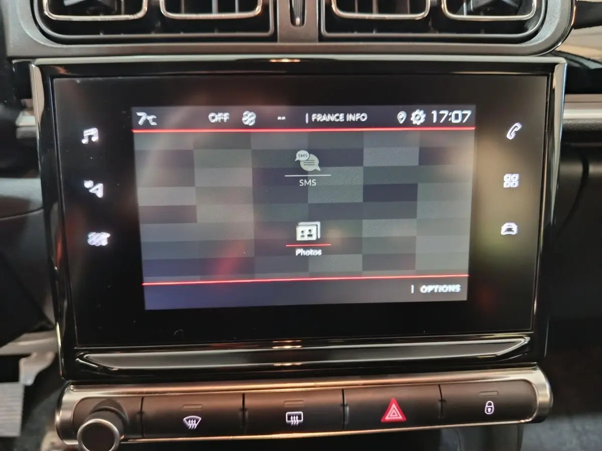 Écran tactile central de la Citroën C3 gris foncé 2024, affichant menu SMS et photos, vue rapprochée intérieure.