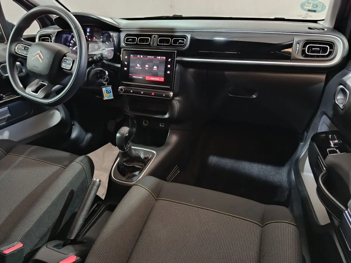 Vue intérieure côté conducteur de la Citroën C3 2024 gris foncé, avec tableau de bord tactile et volant multifonctions.
