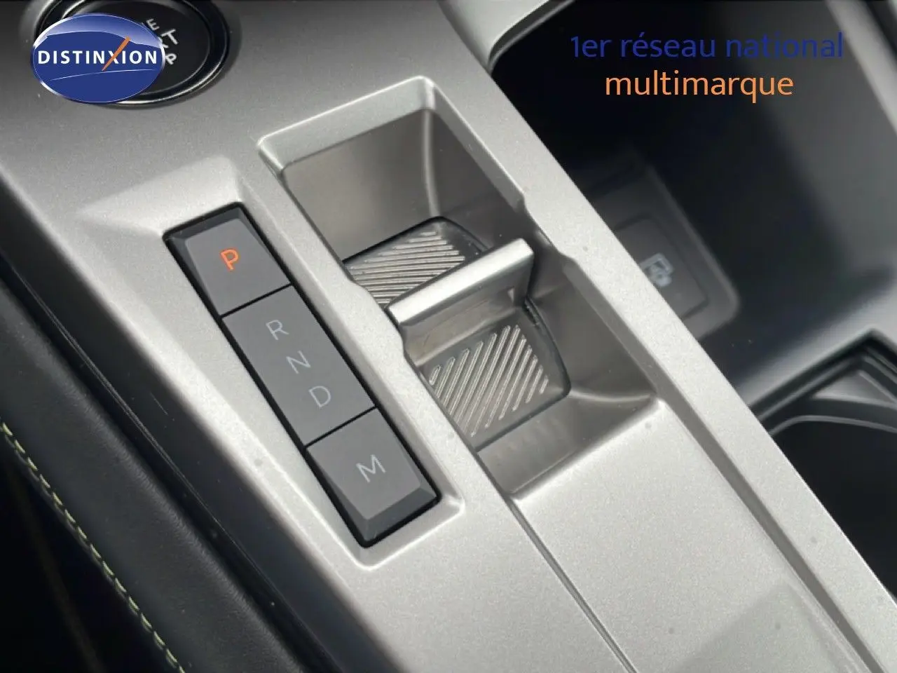 Gros plan sur la console centrale argentée du Peugeot 408 Hybrid 145ch, avec sélecteur de boîte automatique et boutons de vitesses.