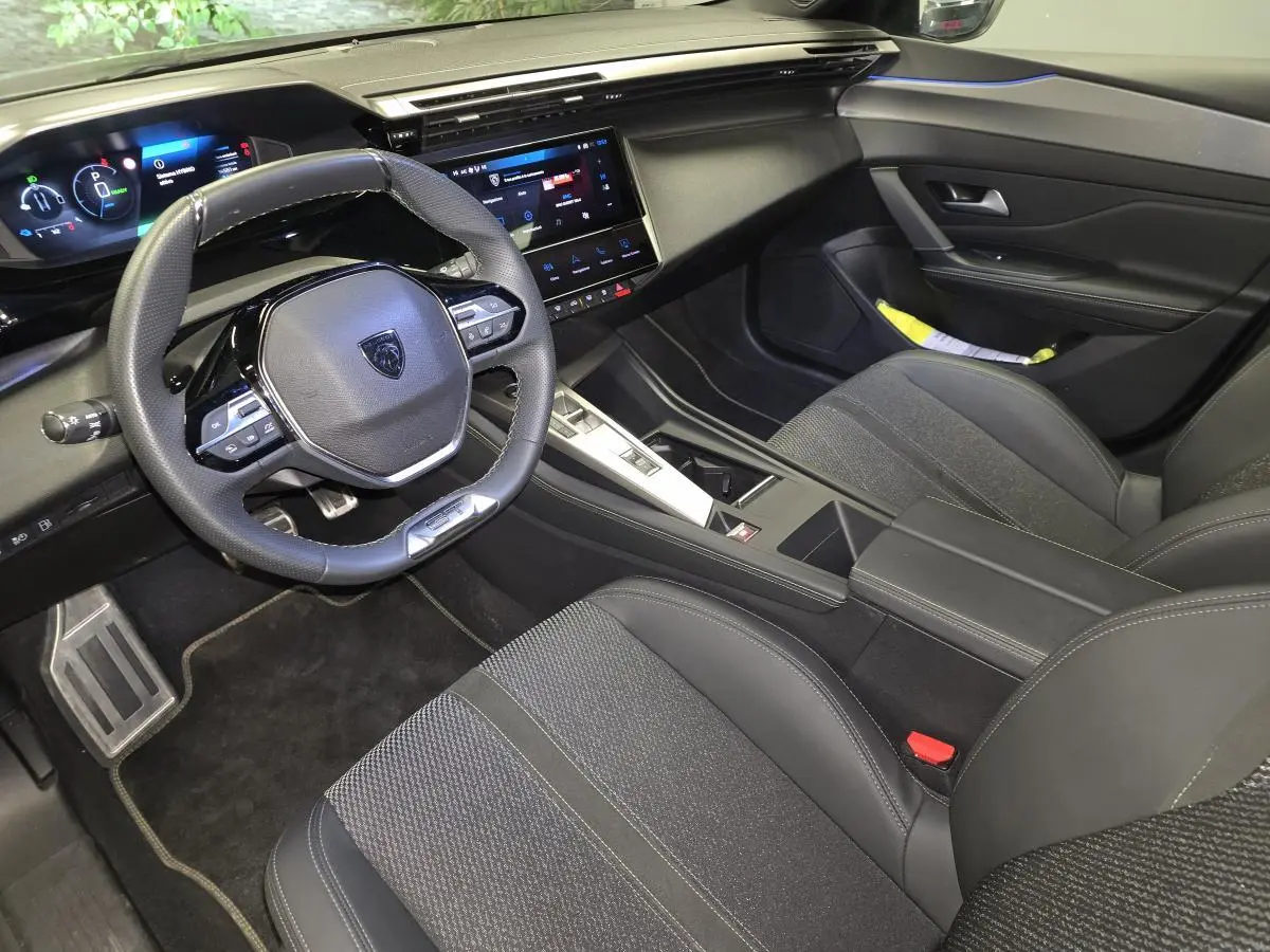 Vue intérieure côté conducteur de la Peugeot 408 gris, avec tableau de bord numérique et volant cuir perforé.