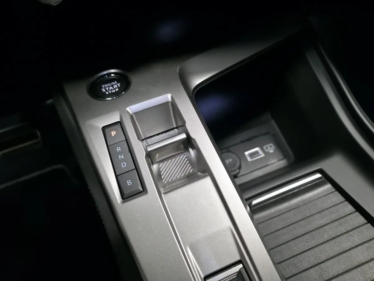 Vue rapprochée de la console centrale grise avec sélecteur de boîte auto et bouton start/stop du Peugeot 408 hybride rechargeable.