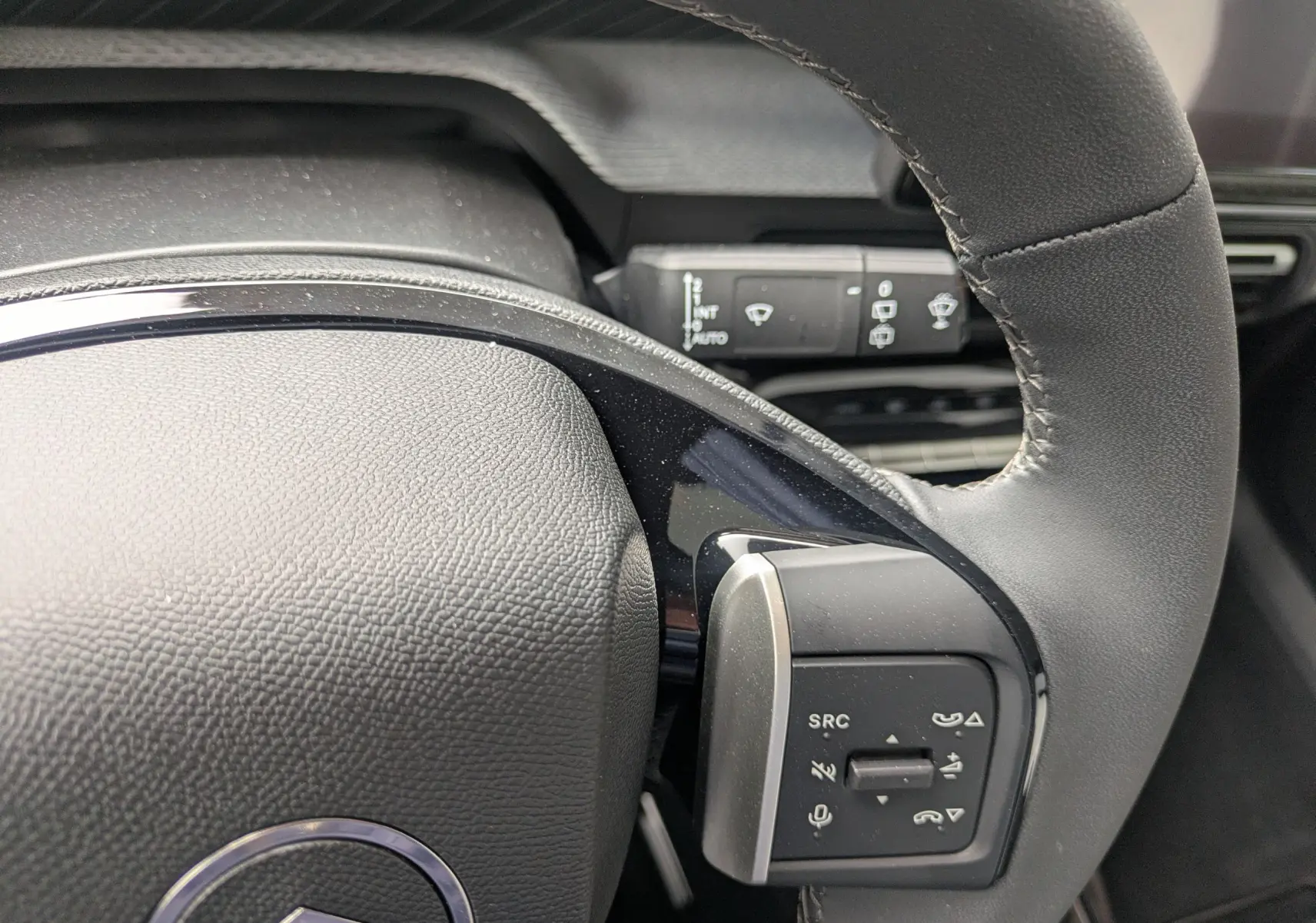 Gros plan sur le volant noir du Citroën C3 Aircross 2026, avec commandes intégrées et détails de la commande d’essuie-glace en arrière-plan.
