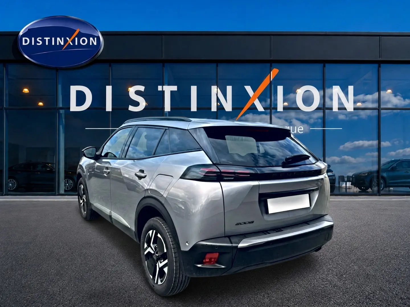 Peugeot 2008 gris artense en 3/4 arrière droit, avec jantes alu et feux arrière LED devant showroom Distinxion.