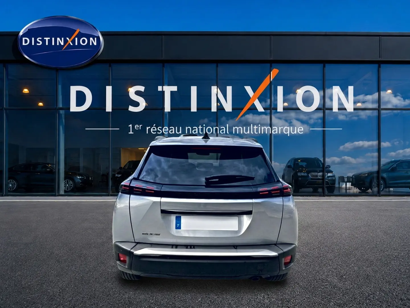 Vue arrière d'un Peugeot 2008 gris artense garé devant une vitrine avec logo Distinxion.