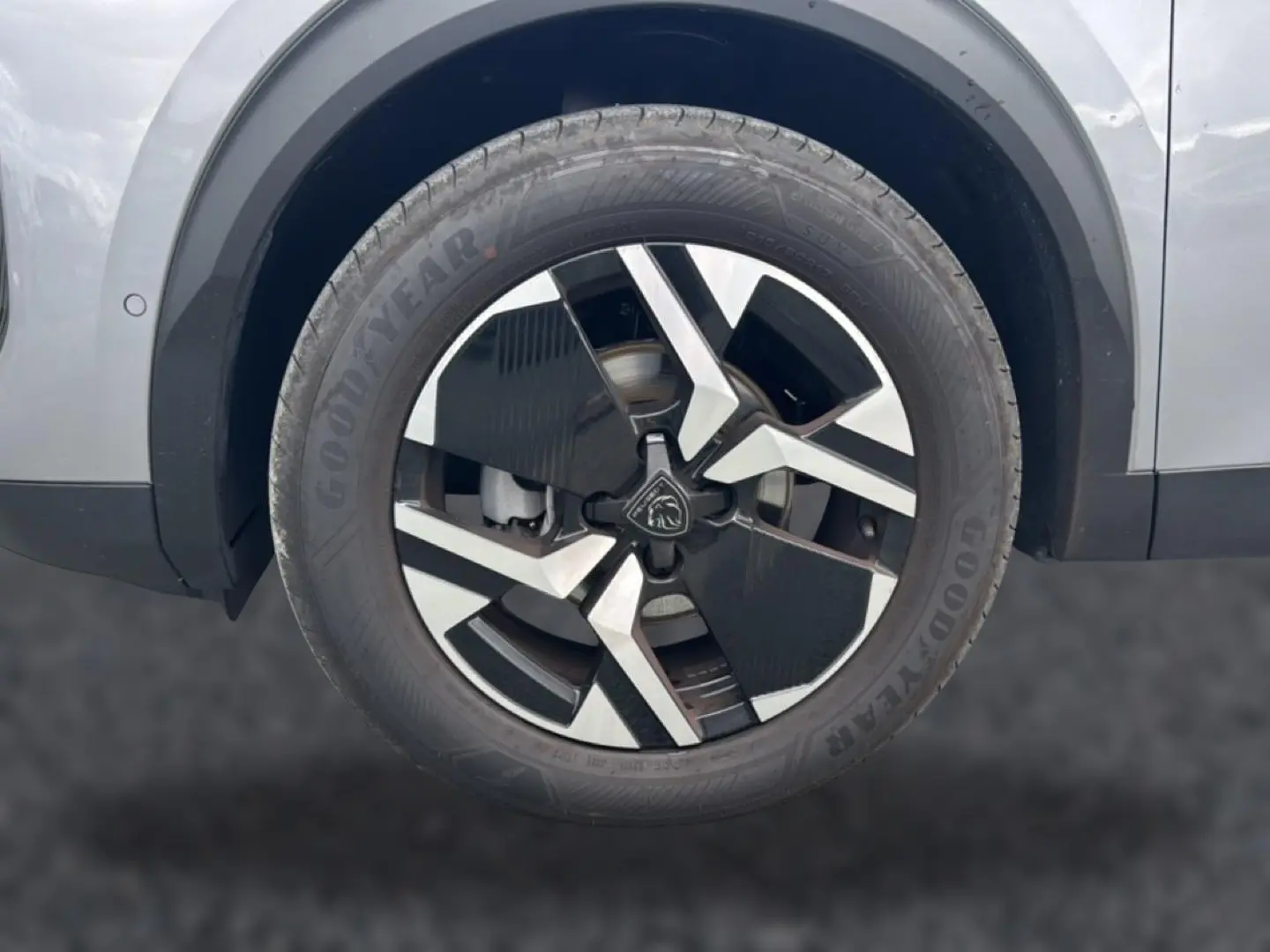 Gros plan sur la roue avant droite gris artense du Peugeot 2008 1.2 100 allure avec jante alu bicolore et pneu Goodyear.
