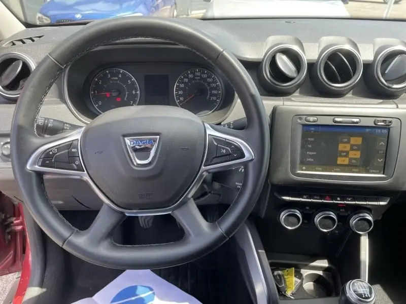 Vue intérieure du tableau de bord du Dacia Duster 2020 rouge métal, avec volant multifonction et écran tactile central.