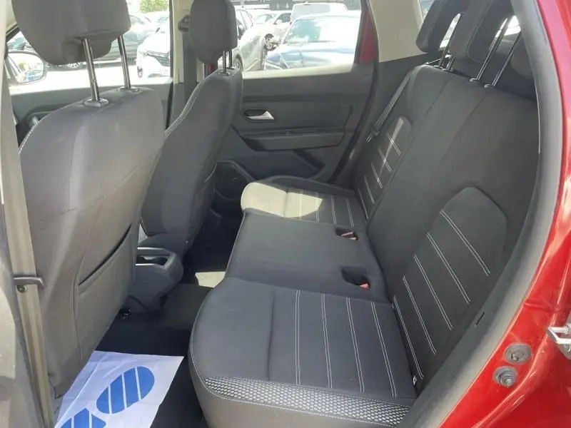 Vue intérieure arrière du Dacia Duster rouge métal 2020, montrant les sièges arrière en tissu noir avec surpiqûres blanches.