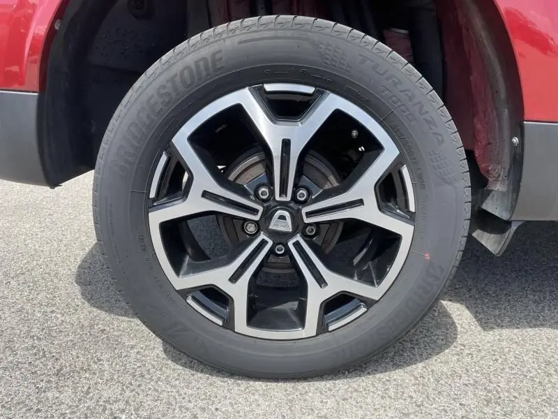 Gros plan sur la roue avant droite du Dacia Duster rouge métal 2020, mettant en valeur la jante alliage au design moderne.