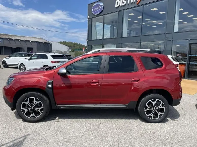 Vue de profil côté gauche d'un Dacia Duster TCE 150 Prestige 4x2 rouge métal avec jantes alliage distinctives.