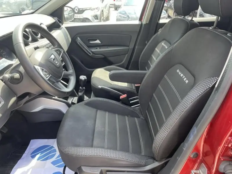 Vue intérieure côté conducteur du Dacia Duster TCE 150 Prestige 4x2 rouge métal de 2020 avec sièges noirs marqués Duster.