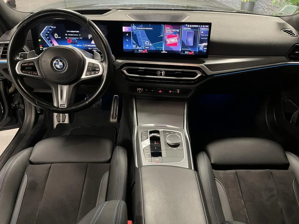 Vue intérieure avant de la BMW Série 3 G21 M Sport 320e noire, tableau de bord numérique et console centrale moderne.