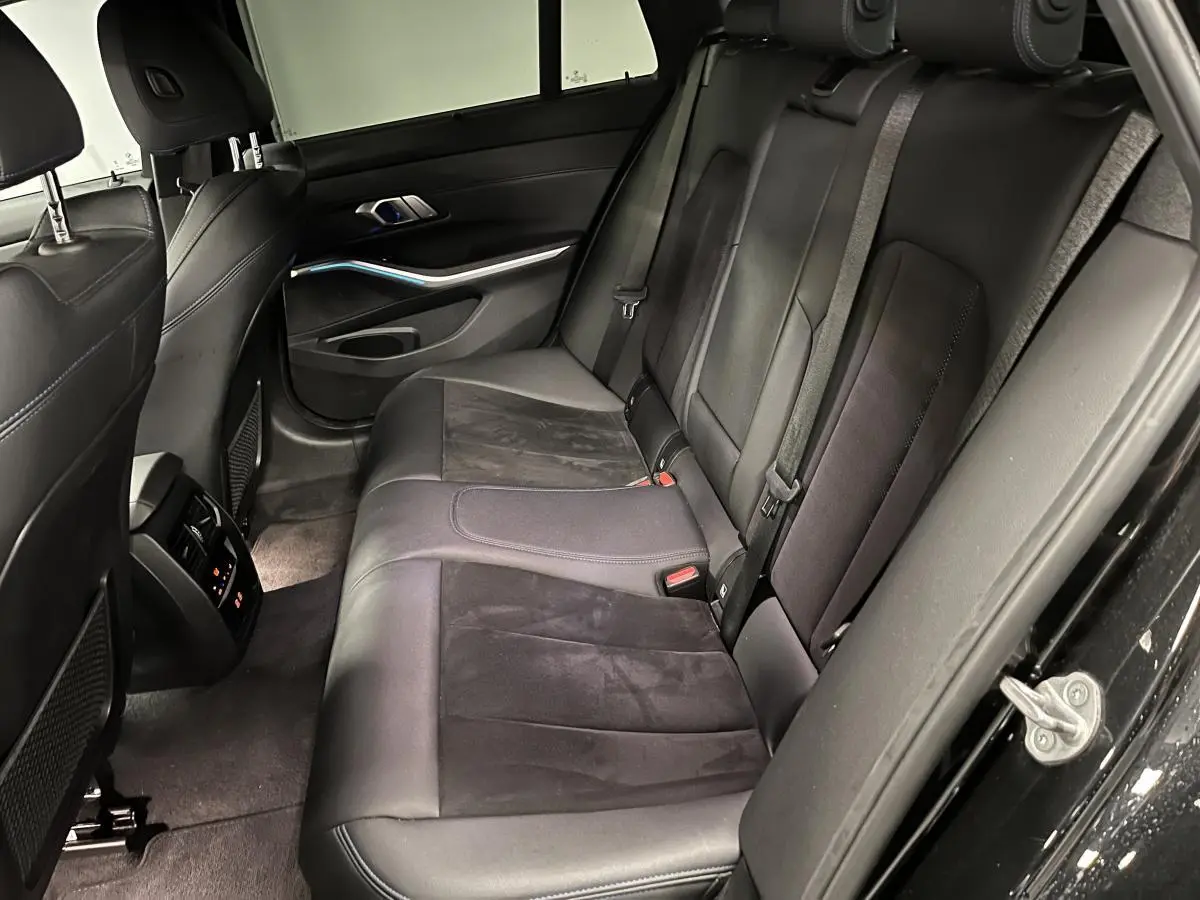 Vue côté droit de l'intérieur arrière noir de la BMW Série 3 320e Touring M Sport avec sellerie cuir et Alcantara.