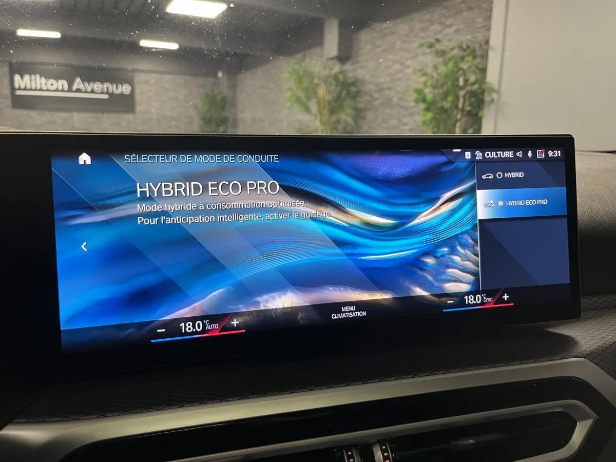 Écran BMW Live Cockpit affichant le mode de conduite Hybrid Eco Pro dans une Série 3 Touring 320e noire, vue intérieure frontale.