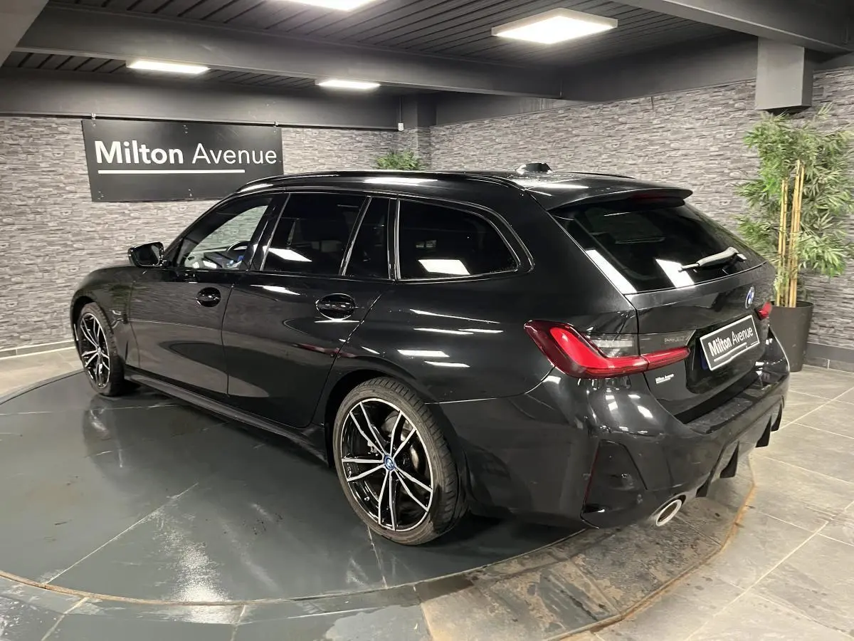 BMW Série 3 Touring 320e noire vue 3/4 arrière droit, jantes M sport bicolores et double sortie d'échappement chrome