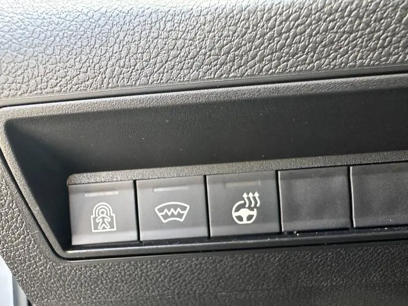 Gros plan sur les boutons de commande du tableau de bord du Citroën Berlingo gris Artense 2024, avec symbole de verrouillage, dégivrage et volant chauffant.