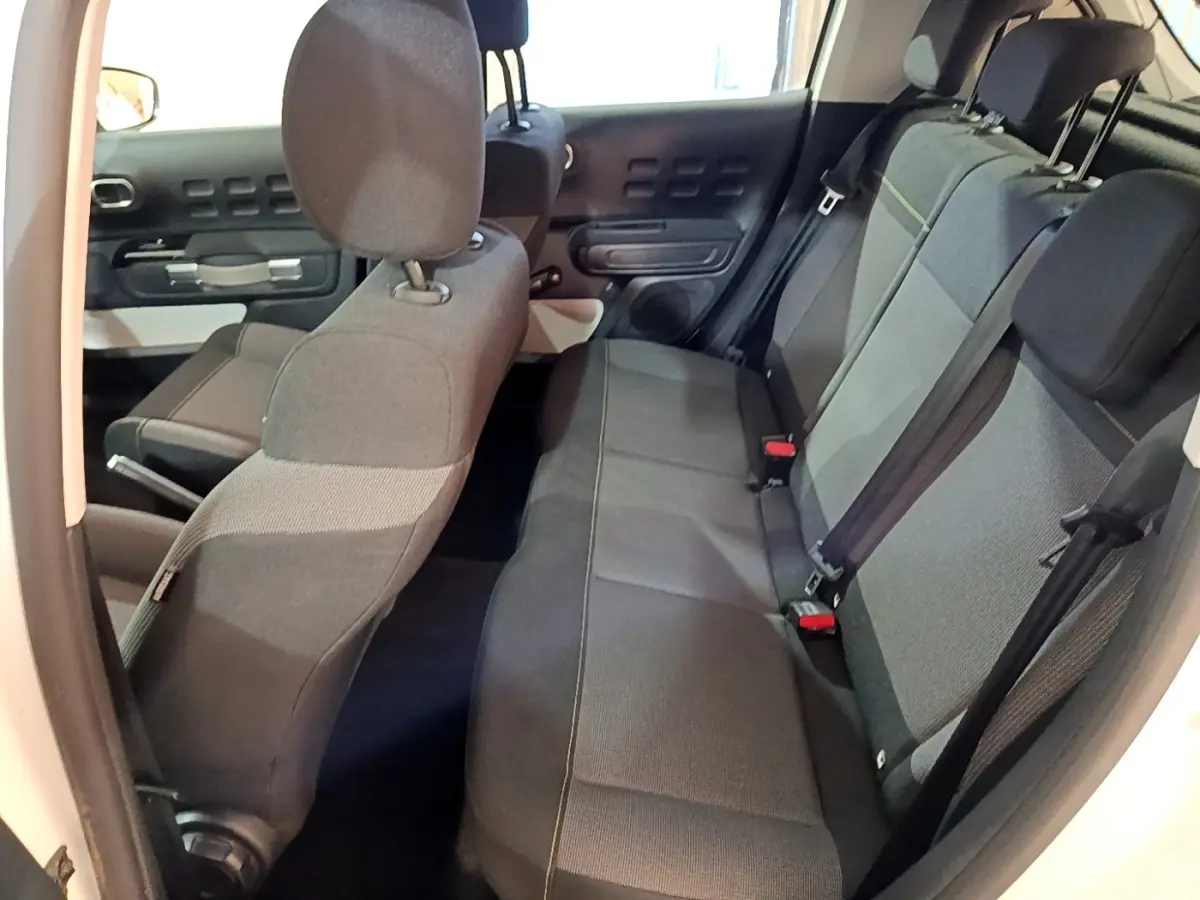 Vue intérieure côté droit montrant la banquette arrière grise et les sièges avant du Citroën C3 blanc 2020.