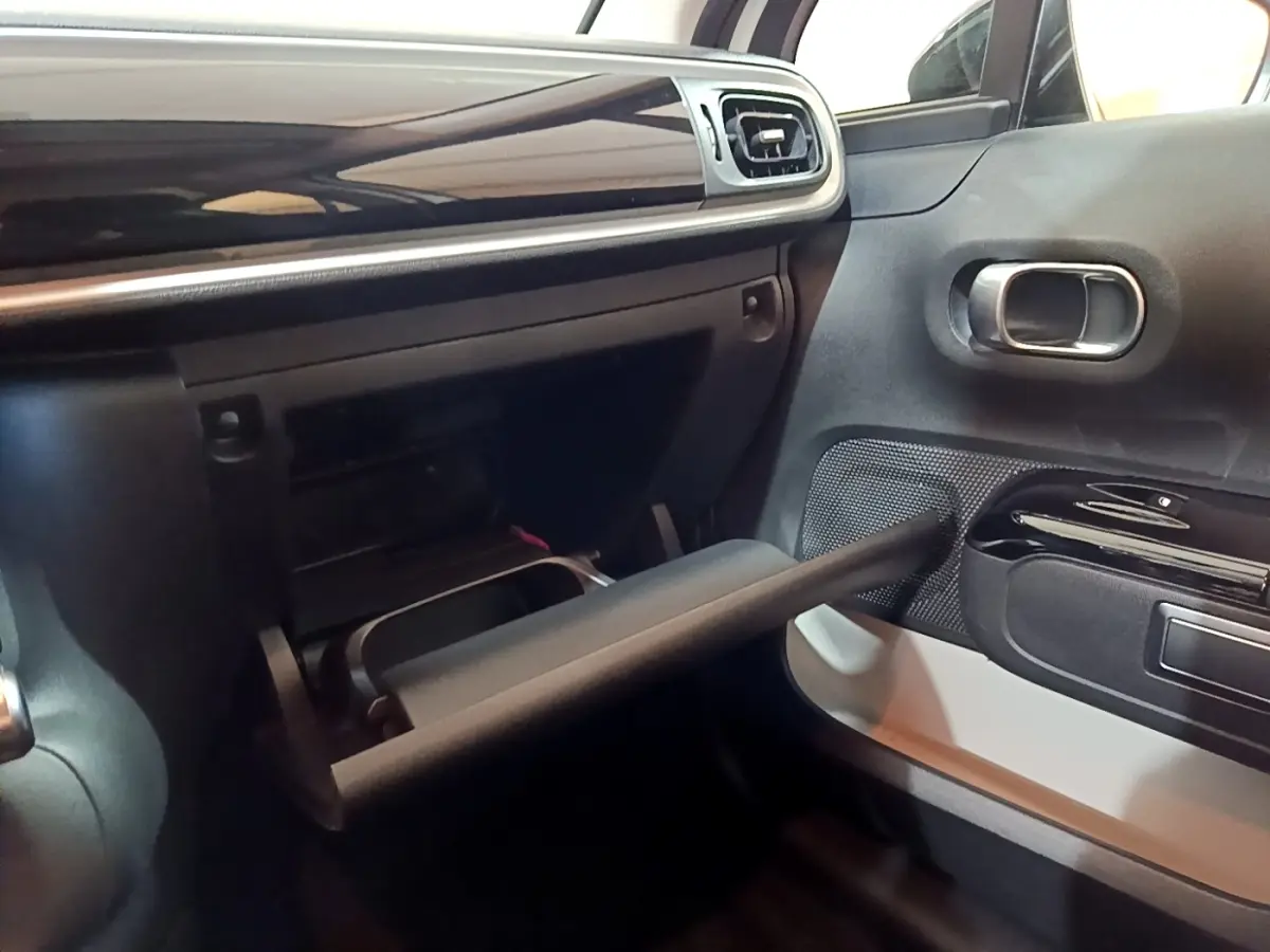 Vue intérieure côté passager du tableau de bord noir et gris avec boîte à gants ouverte d'une Citroën C3 blanche 2020.