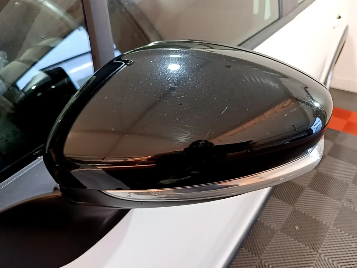 Gros plan sur le rétroviseur noir côté conducteur d'une Citroën C3 blanche vue de profil gauche.