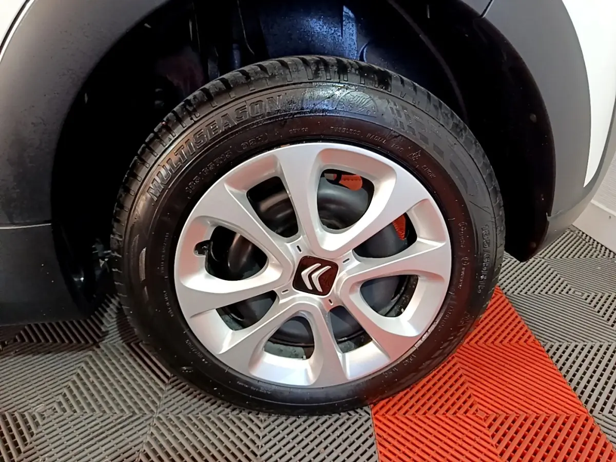 Gros plan sur la roue avant droite d'une Citroën C3 blanche, mettant en valeur la jante argentée à cinq branches.