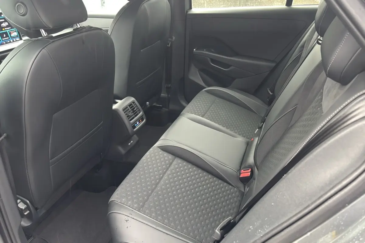 Vue intérieure arrière droite du Volkswagen T-Roc gris loup, montrant la banquette tissu et cuir avec accoudoir central.