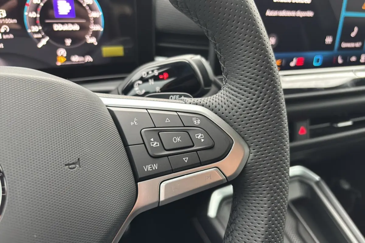 Gros plan sur les commandes multifonctions du volant cuir perforé du Volkswagen T-Roc 2026 version R-Line.