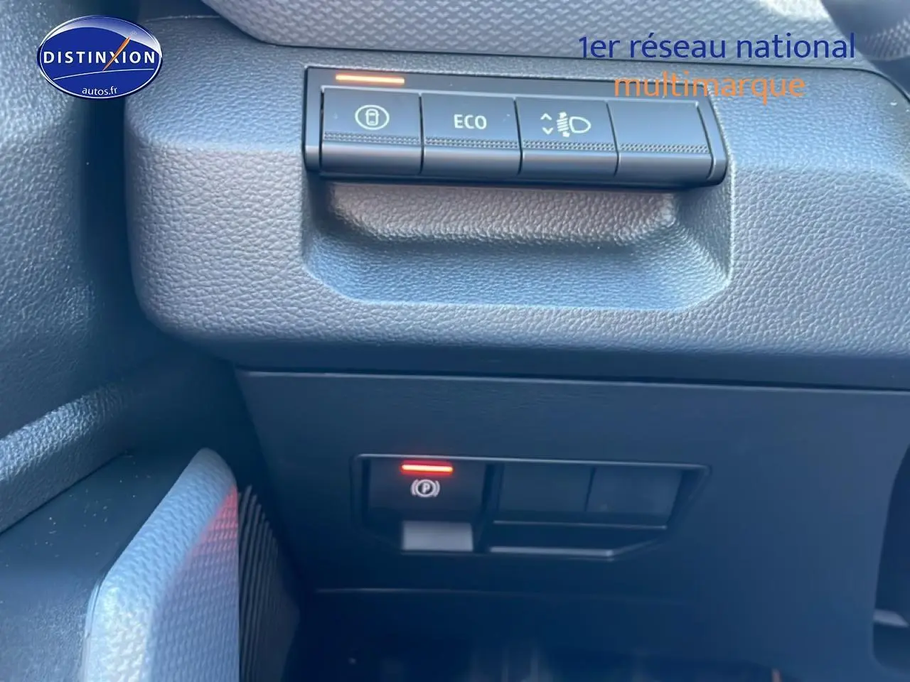 Gros plan sur les commandes du tableau de bord côté gauche du Dacia Duster noir 2026, avec bouton Eco et frein à main électrique.