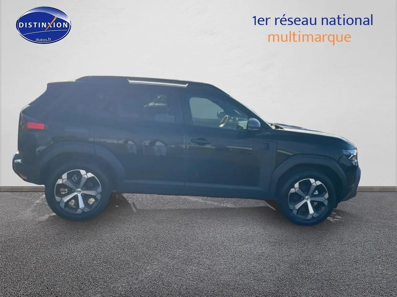 Vue de profil côté gauche d'un Dacia Duster noir 2026 avec jantes alliage et barres de toit visibles.