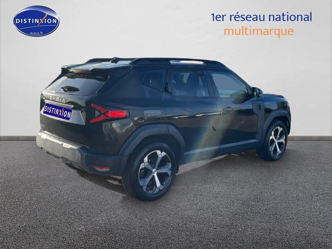 Vue 3/4 arrière droit du Dacia Duster noir 2026 avec jantes alu et barres de toit visibles.