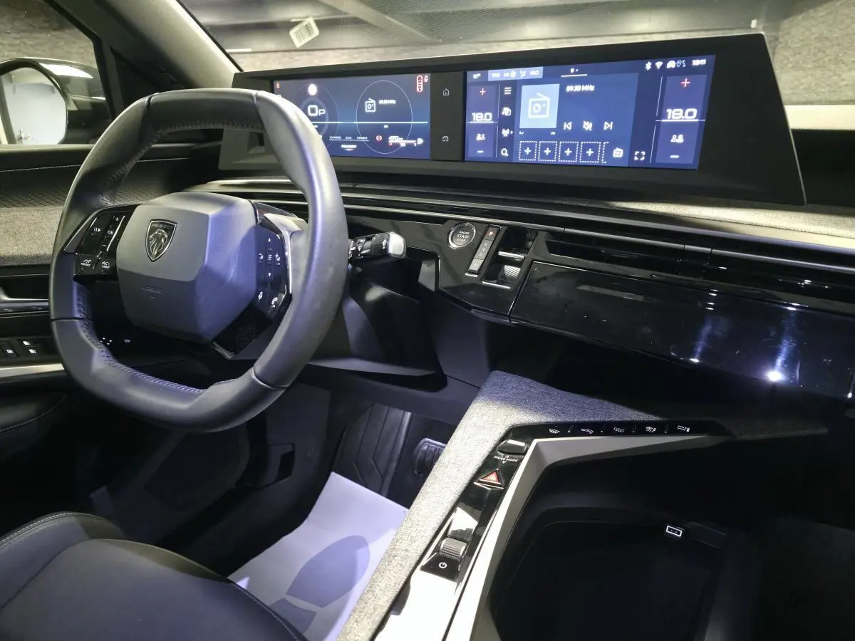Intérieur avant droit du Peugeot 3008 bleu 2025, volant compact, double écran HD et console centrale tissu Rimini.