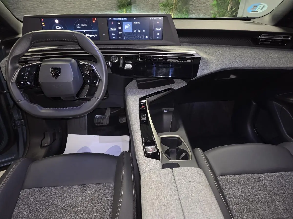 Intérieur avant du Peugeot 3008 bleu 2025, tableau de bord avec double écran HD et volant compact cuir noir.