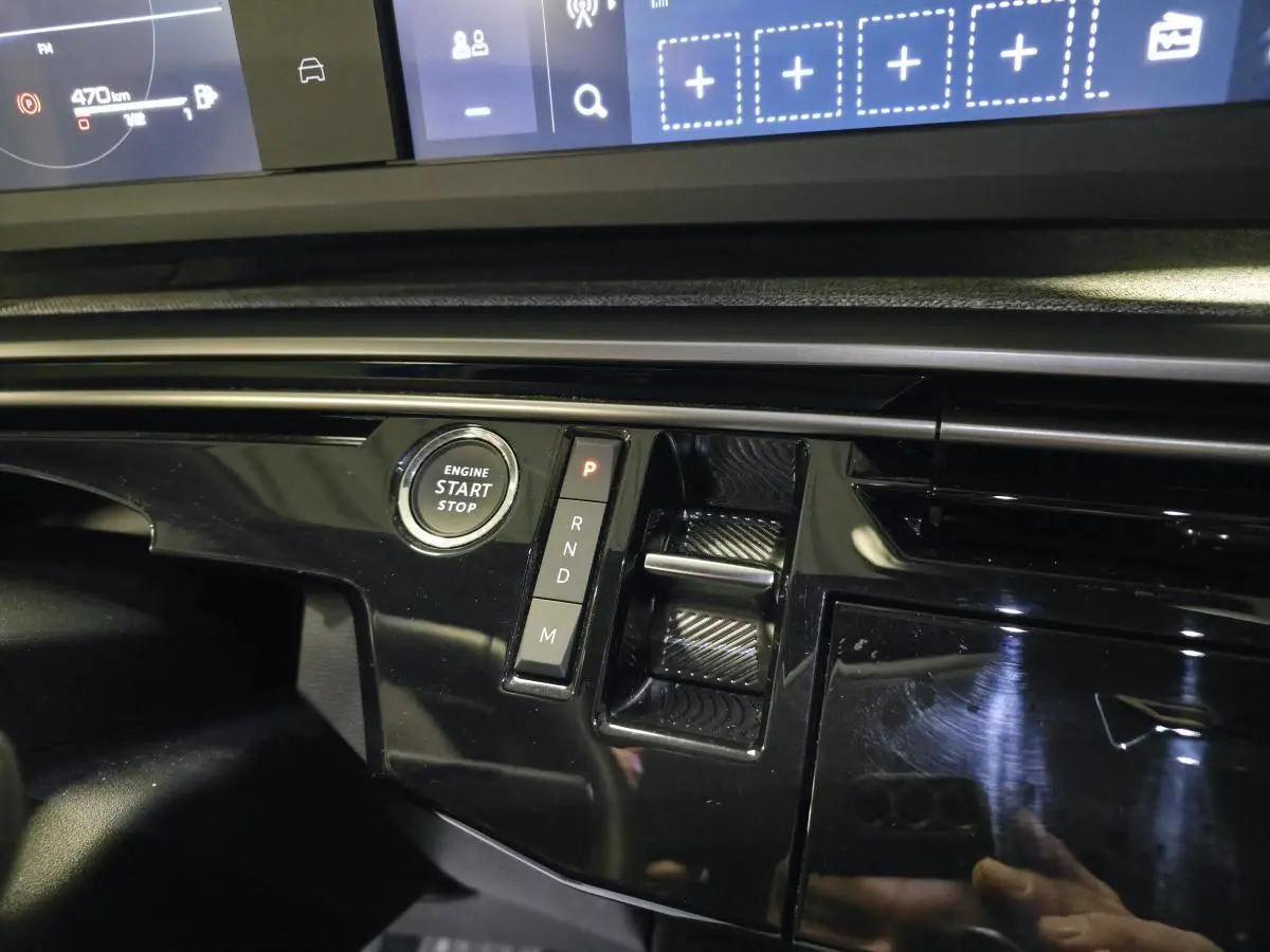 Détail de la console centrale noire laquée du Peugeot 3008 bleu, avec bouton start/stop et commandes de boîte auto.