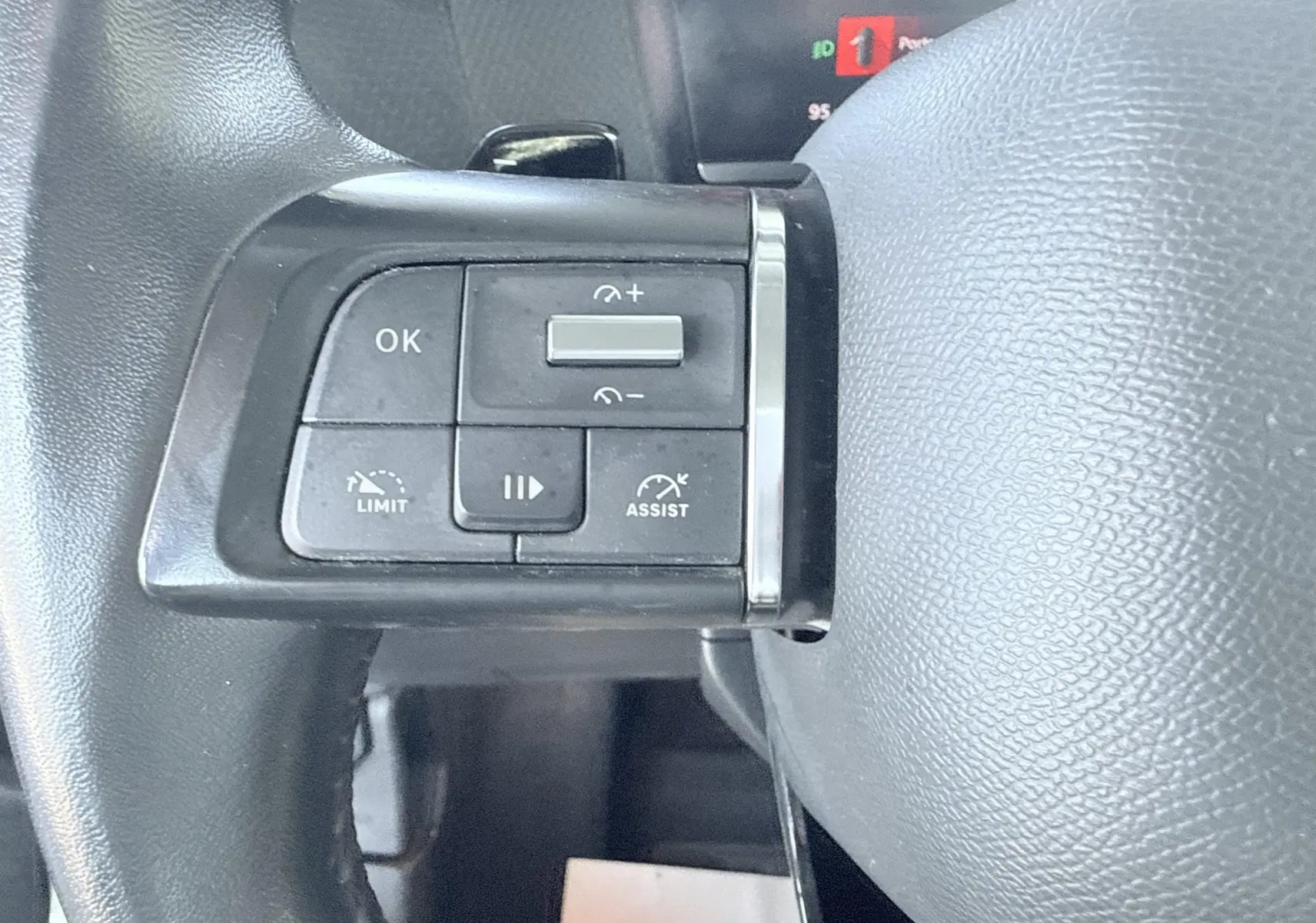 Gros plan sur les commandes de régulateur et limiteur de vitesse au volant noir d'une Citroën C4 blanche de 2023.