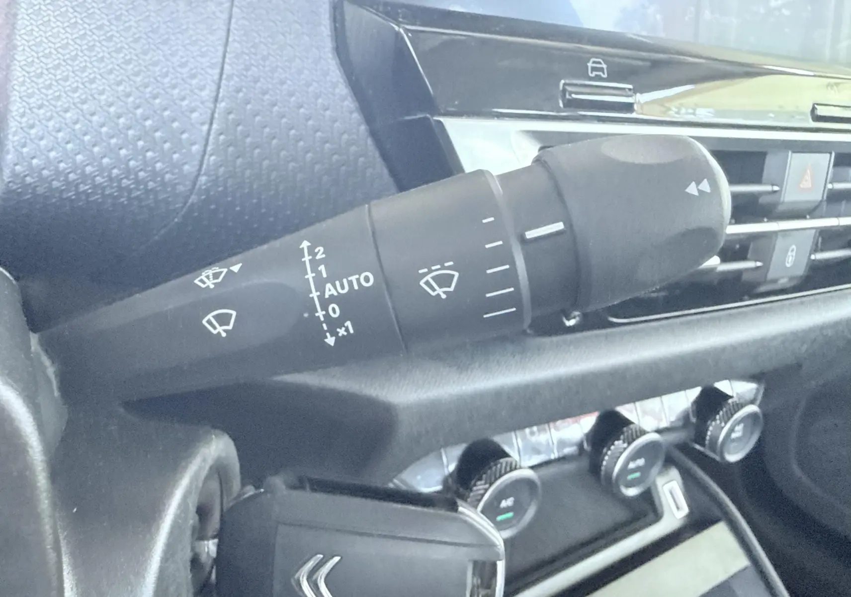 Gros plan sur la commande d’essuie-glace à gauche du volant dans l’habitacle gris noir d’une Citroën C4 blanche.