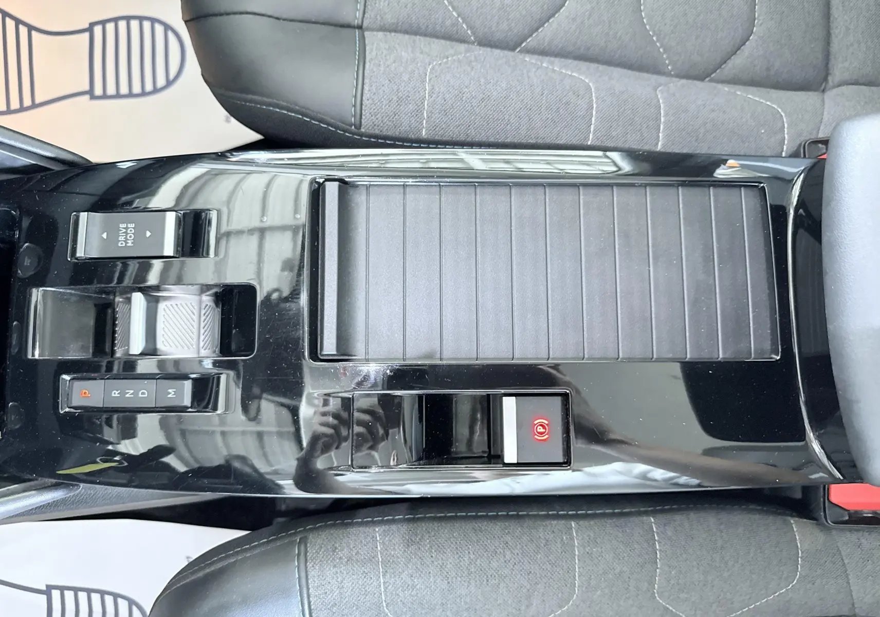 Vue plongeante sur la console centrale noire brillante de la Citroën C4 avec levier de vitesse automatique et bouton frein à main électrique.