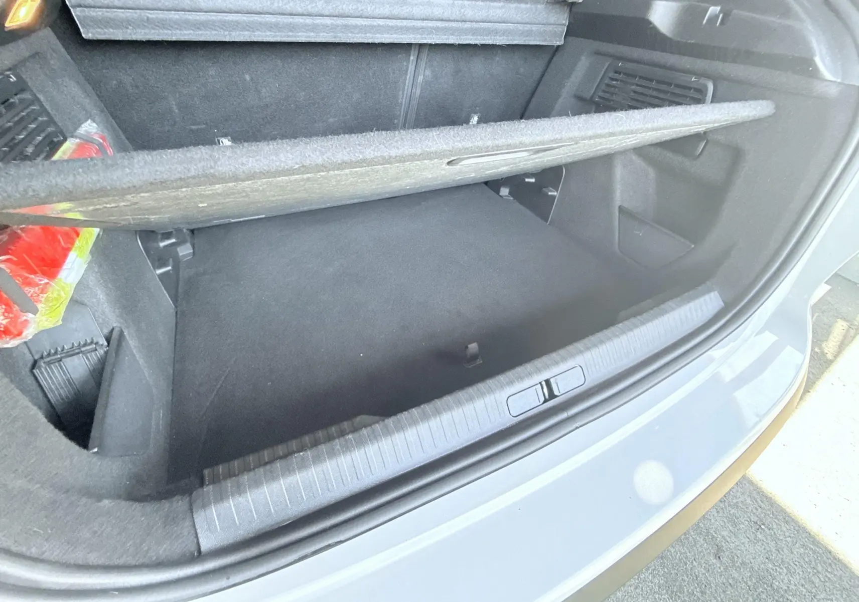 Vue ouverte du coffre arrière d'une Citroën C4 blanche, montrant le compartiment de rangement avec cache amovible.