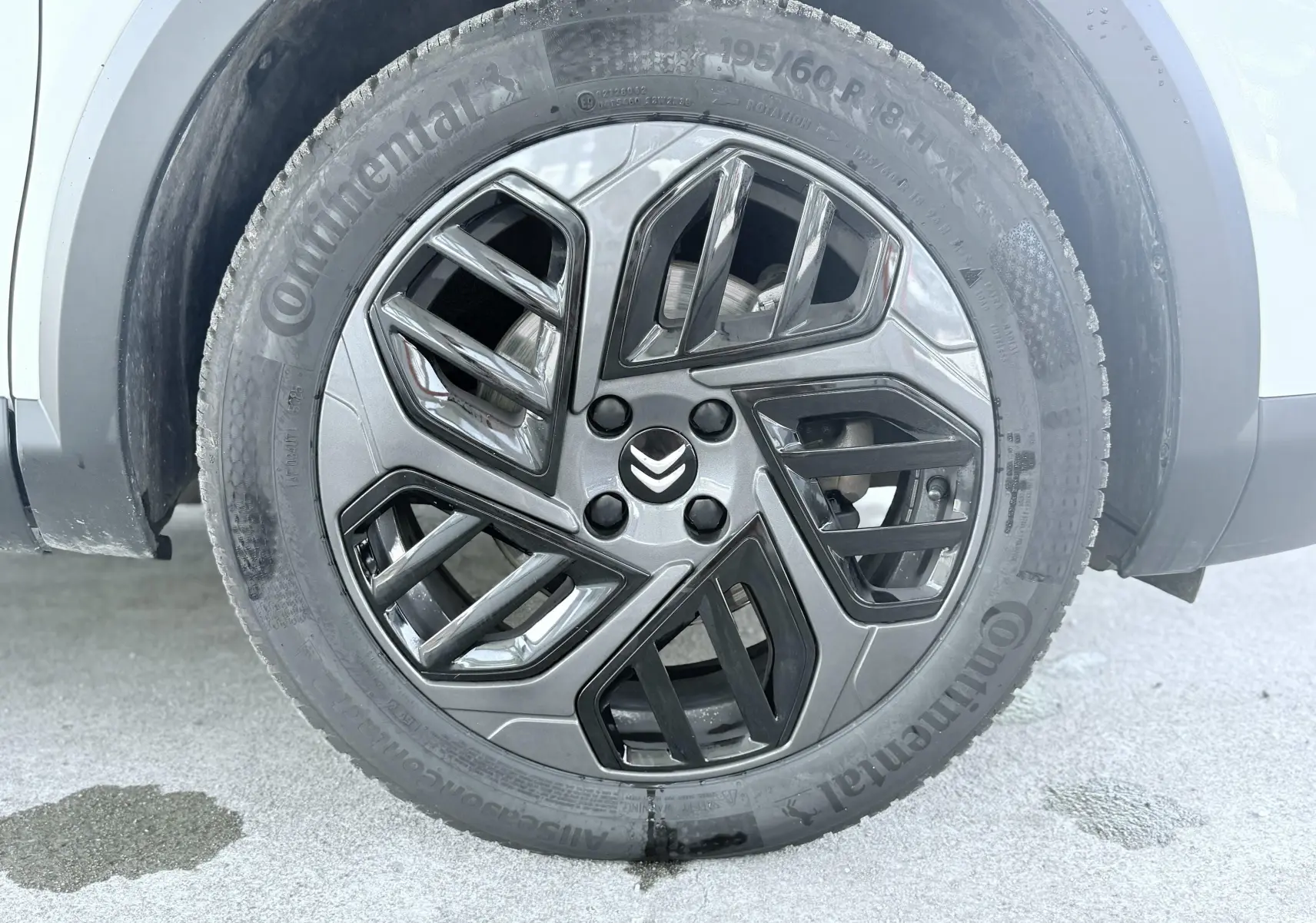 Gros plan sur la roue avant droite blanche d'une Citroën C4 2023 avec jante alliage noire et grise au design géométrique.