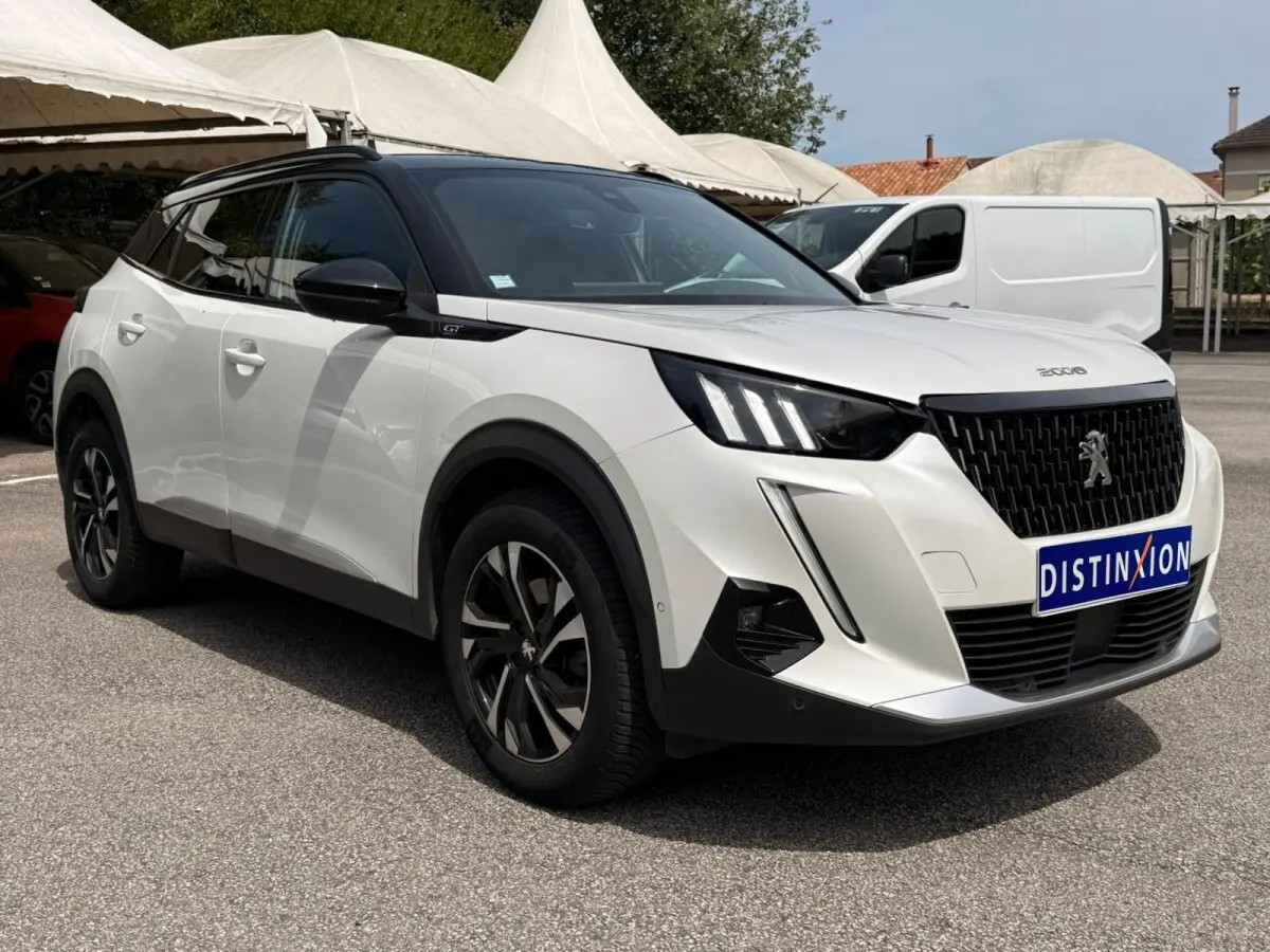 Peugeot 2008 blanc en 3/4 avant droit, avec calandre noire et jantes alliage distinctives, stationné en extérieur.