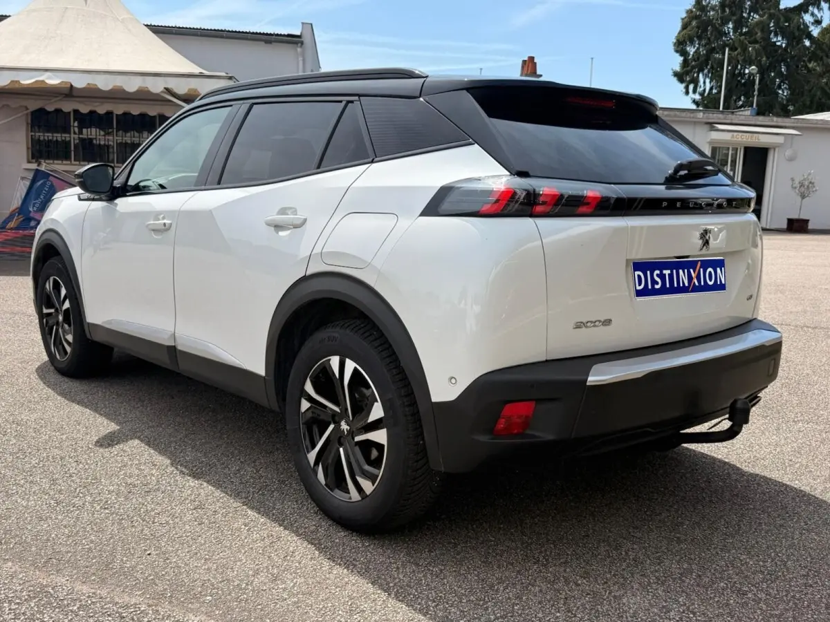 Vue 3/4 arrière droite d'un Peugeot 2008 blanc avec toit noir et feux arrière à griffes rouges distinctifs.