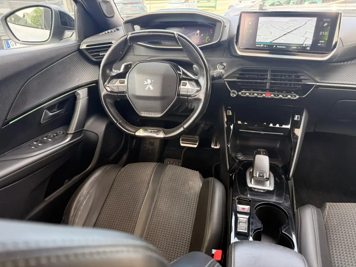Vue intérieure de face du poste de conduite du Peugeot 2008 blanc, avec volant compact et écran tactile central lumineux.